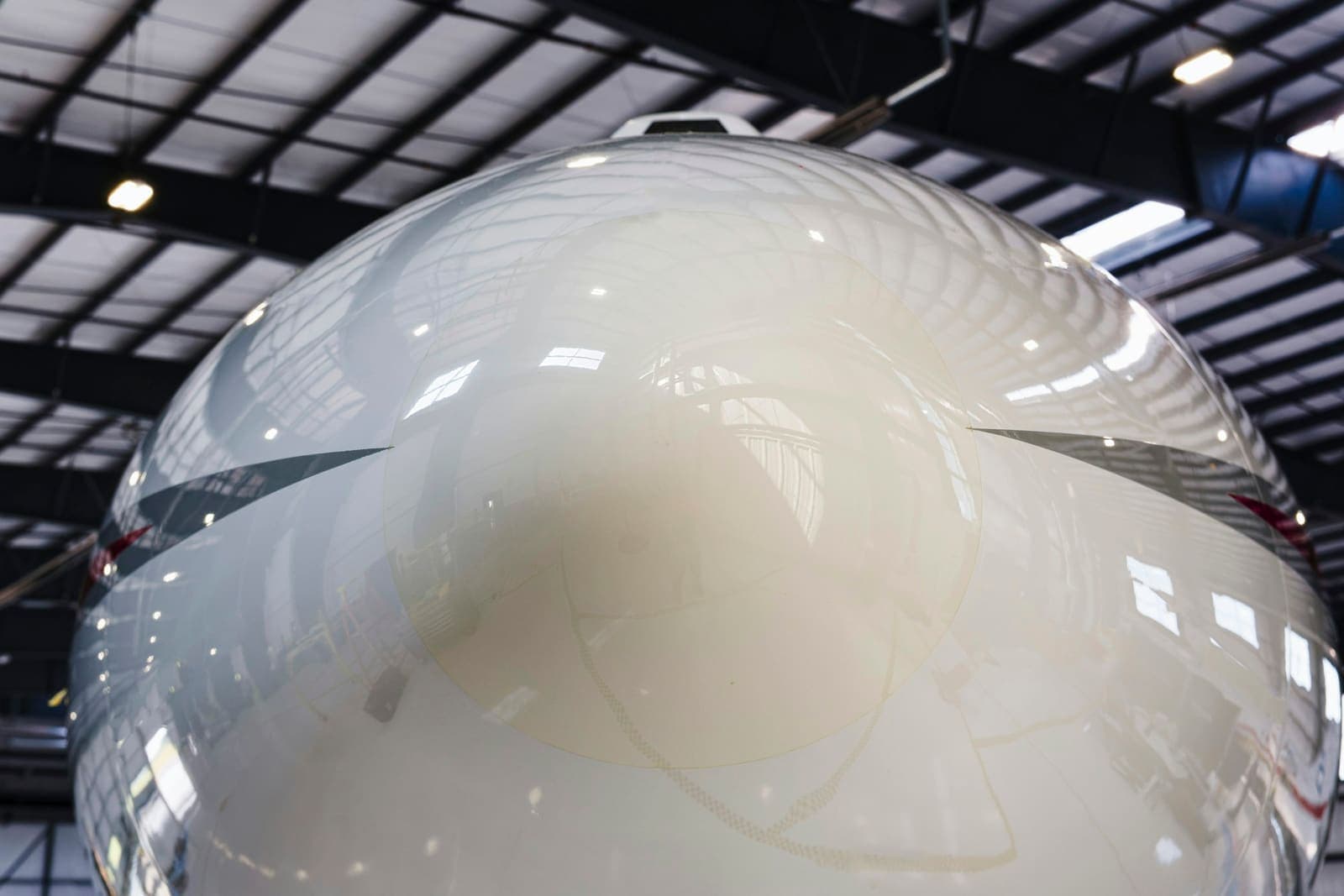 A private jet's polished nose beneath a hangar roof