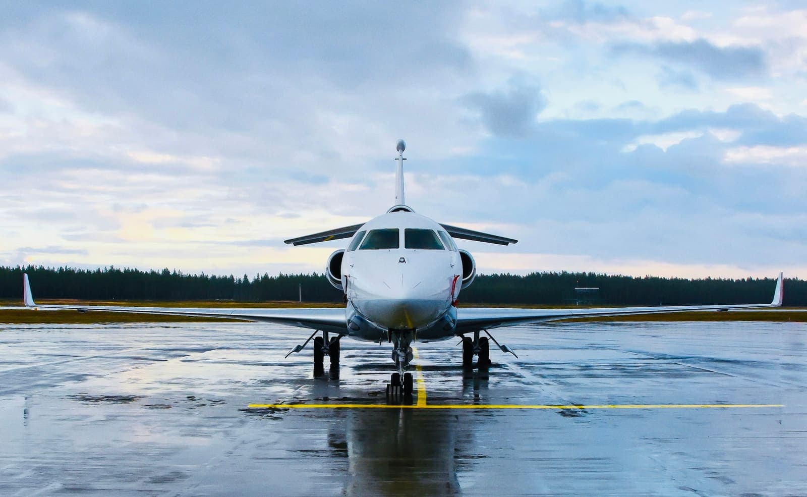 A heavy business jet on a wet runway under a broken sky