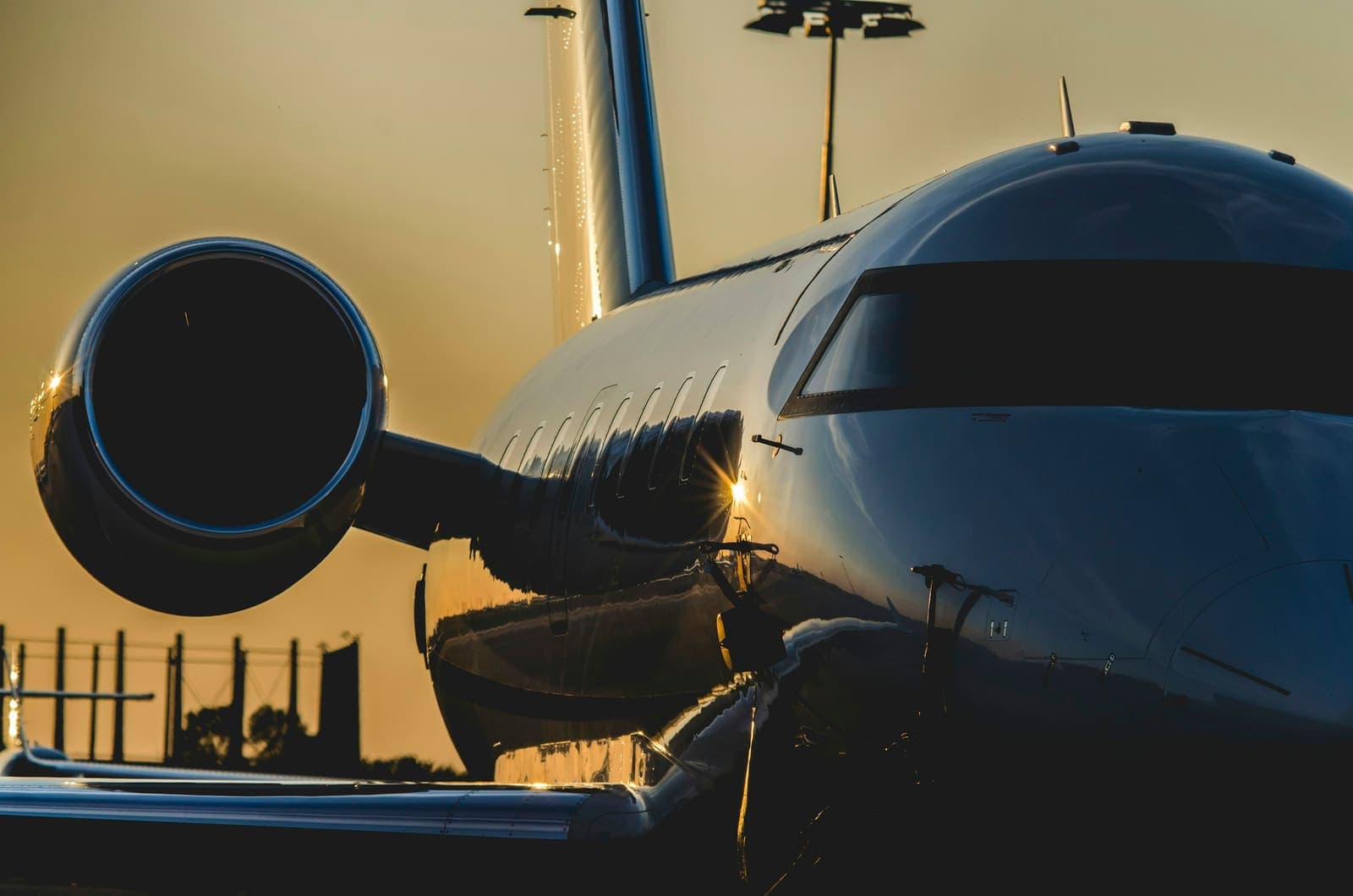 A business jet nose reflected on the ramp at golden hour